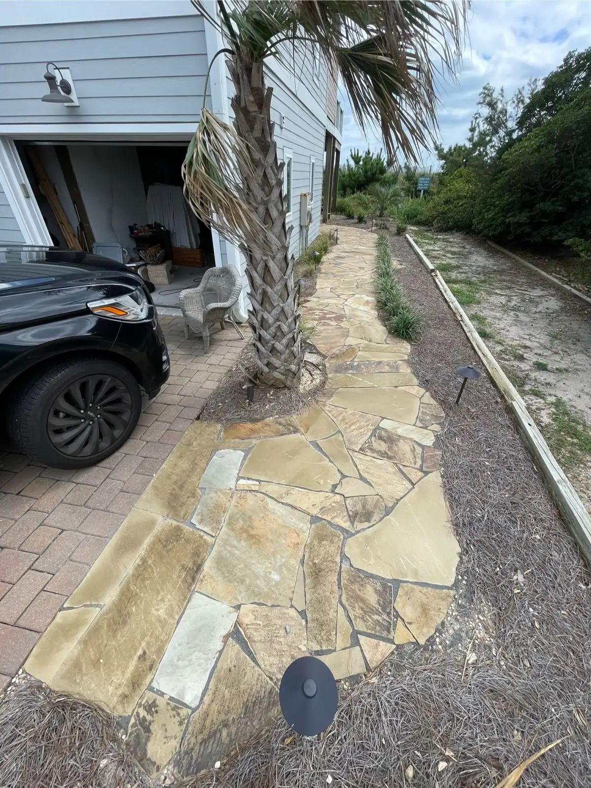 Custom stone seat wall with cap stones alongside paver patio in coastal NC